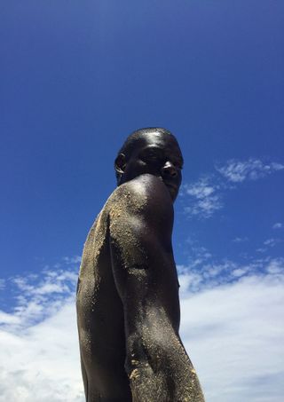 Statue of a man looking over his shoulder with sand on it