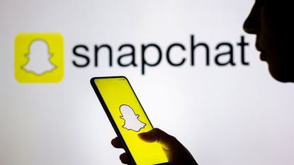 Silhouette holding a smartphone with the Snapchat logo