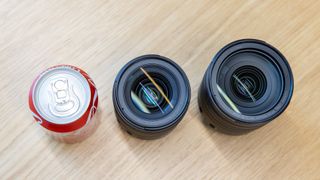 A birds eye view showing a comparison in size between a 330ml drinks can, the Canon RF 28-70mm F2.8 IS STM lens in the middle and the Canon’s RF 24-105mm F4L IS USM on the right.