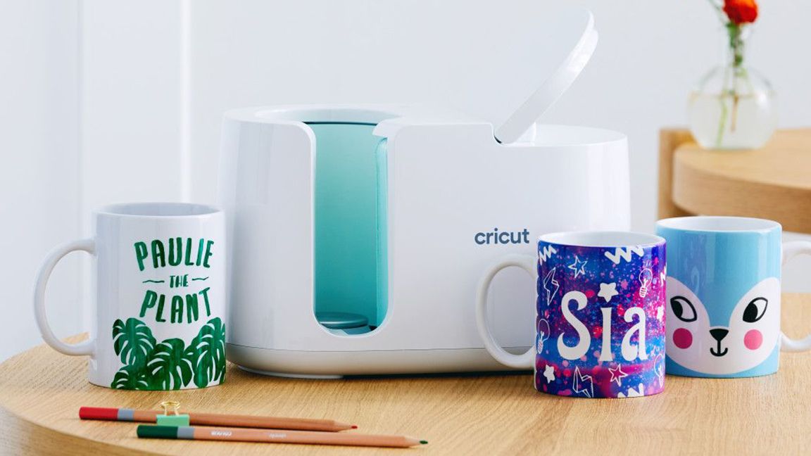 Cricut Mug Press on a table, surrounded by mugs