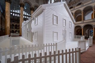 The installation includes a large white house with a white fence.
