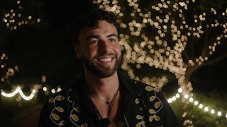 Sammy in a black shirt and standing in front of a tree at night covered in fairly lights for Love Island All Stars