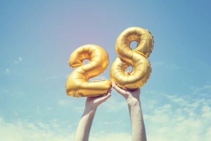  two arms holding up the number "28" against a blue sky 