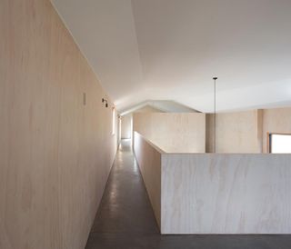 staircase and gallery clad in blonde wood in Chilean house by Ampueroyutronic