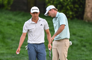 Collin Morikawa walks off the green as Russell Henley gets ready to putt