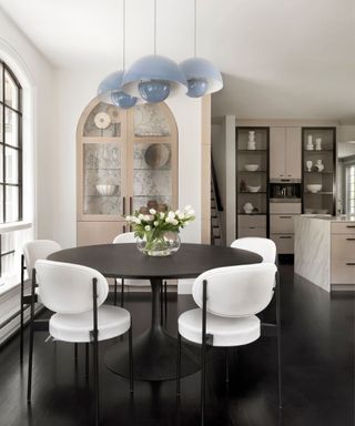 Circular black dining table with white chairs