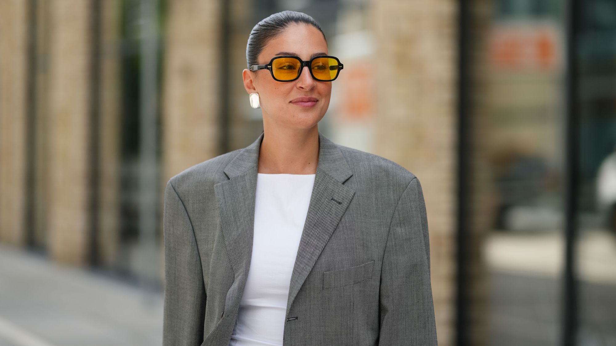 street style shot of woman with slicked bun and glowy makeup