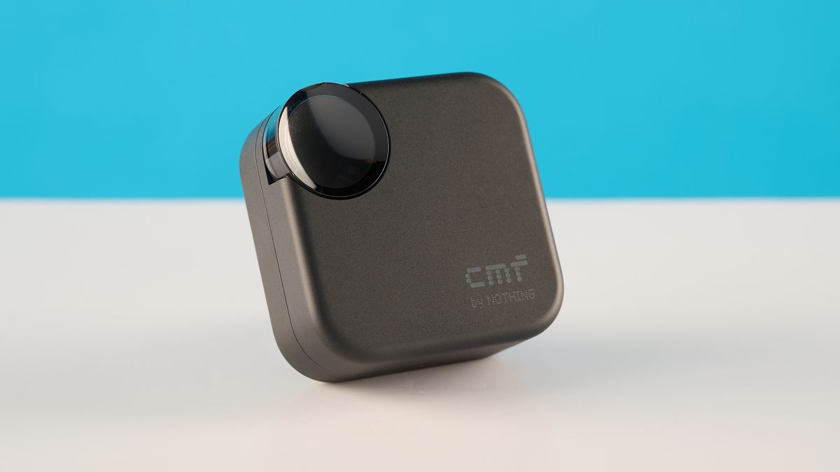 CMF Buds 2 in Dark Gray photographones on a gray table in front of a blue background