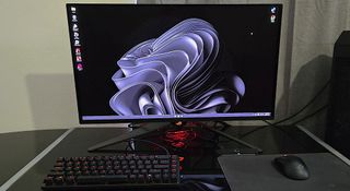 The ROG Swift OLED PG27UCDM on a desk, with a keyboard and mouse in front of it