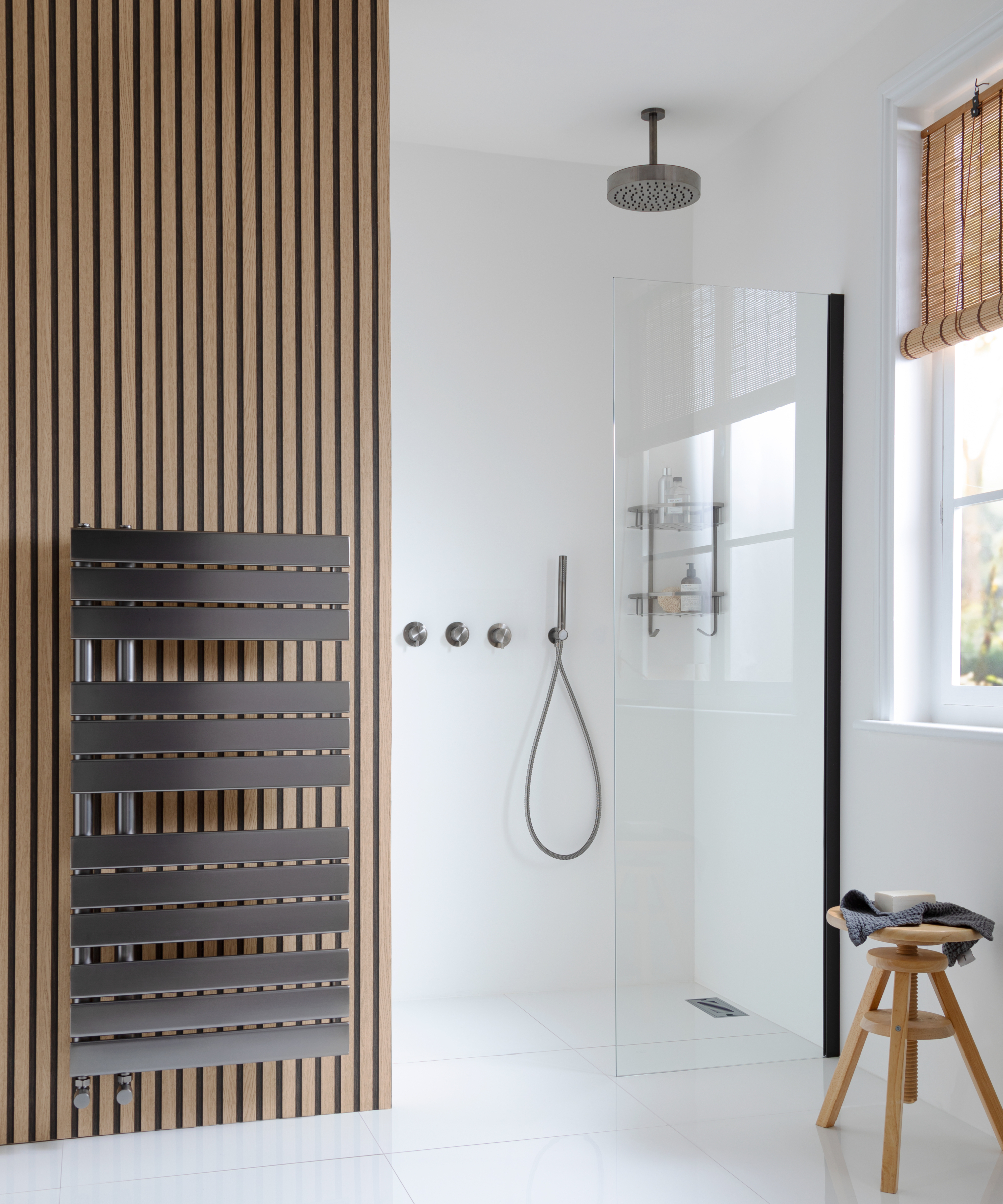 bathroom with walk in shower enclosure, mixer shower on wall, wood panelling feature to side and towel radiator