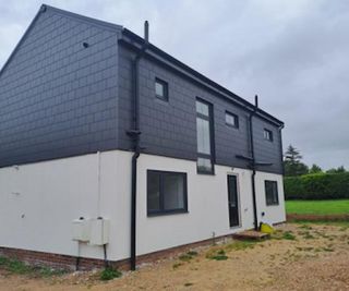 A side-on view of a bungalow extension with grey and white rendered walls