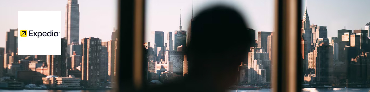 Expedia Logo placed over an auto of focus head looking at New York City from afar