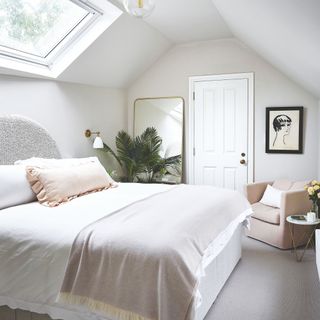 Bedroom in converted loft, with chair, large mirror, plant and large rooflight above the bed