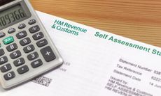 Self-assessment tax return form and calculator on a table.