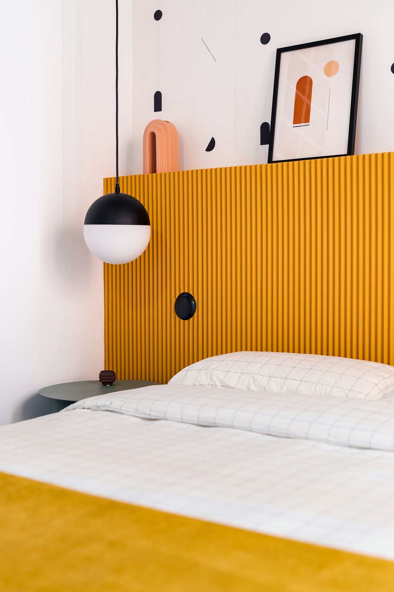 A bedroom with a dark, yellow-painted headboard