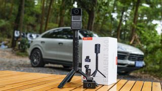 Vantrue E360 dash cam attached to selfie grip on a park bench, alongside the rear cam and product packaging, car in the background