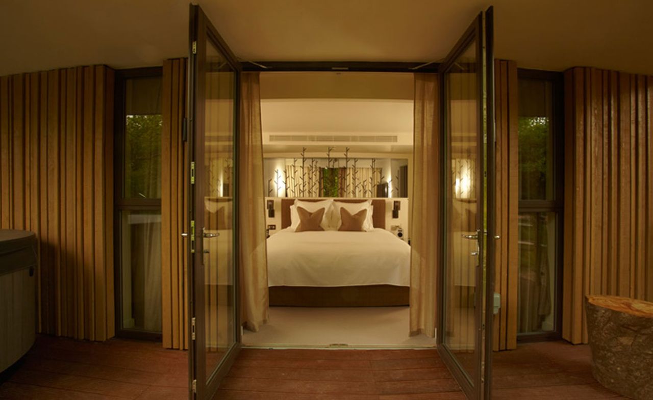 Bedroom at the Treehouse Suites, Chewton Glen Hotel &amp; Spa, Hampshire, UK with white bedding and wooden balcony