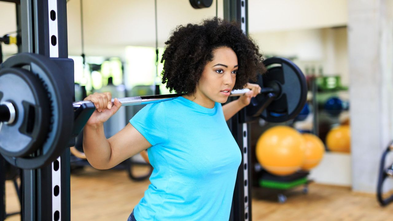 A woman unracking a barbell at the gym ahead of performing a barbell back squat