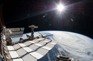 A bright sun, a portion of the International Space Station and Earth's horizon are featured in this image photographed by a spacewalker, using a fish-eye lens attached to an electronic still camera, during the STS-134 mission's fourth spacewalk on May 27,