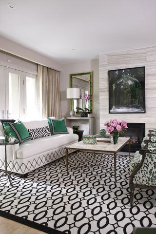 White living room with white sofa, green cushions and black and white geometric rug