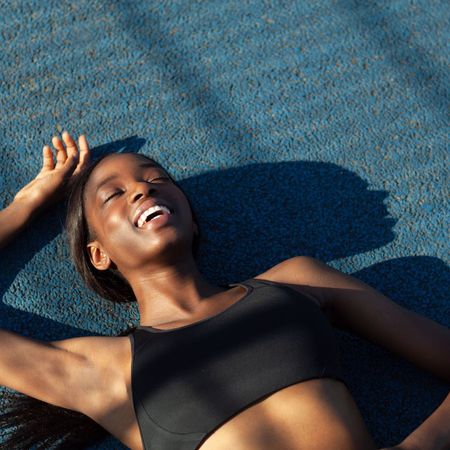 A woman lying down on an athletics track after a workout