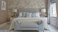 Plush pale blue and cream bedroom with large bedding, throw pillows, teddy ottoman, cherry blossom Fromental wallpaper in cream and blue and floor length curtains