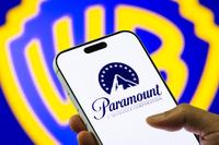 Shot of Warner Bros. logo behind a smart phone showing a Paramount logo.