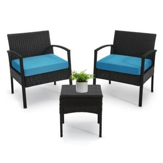 A rattan patio set in black with a table and blue cushions