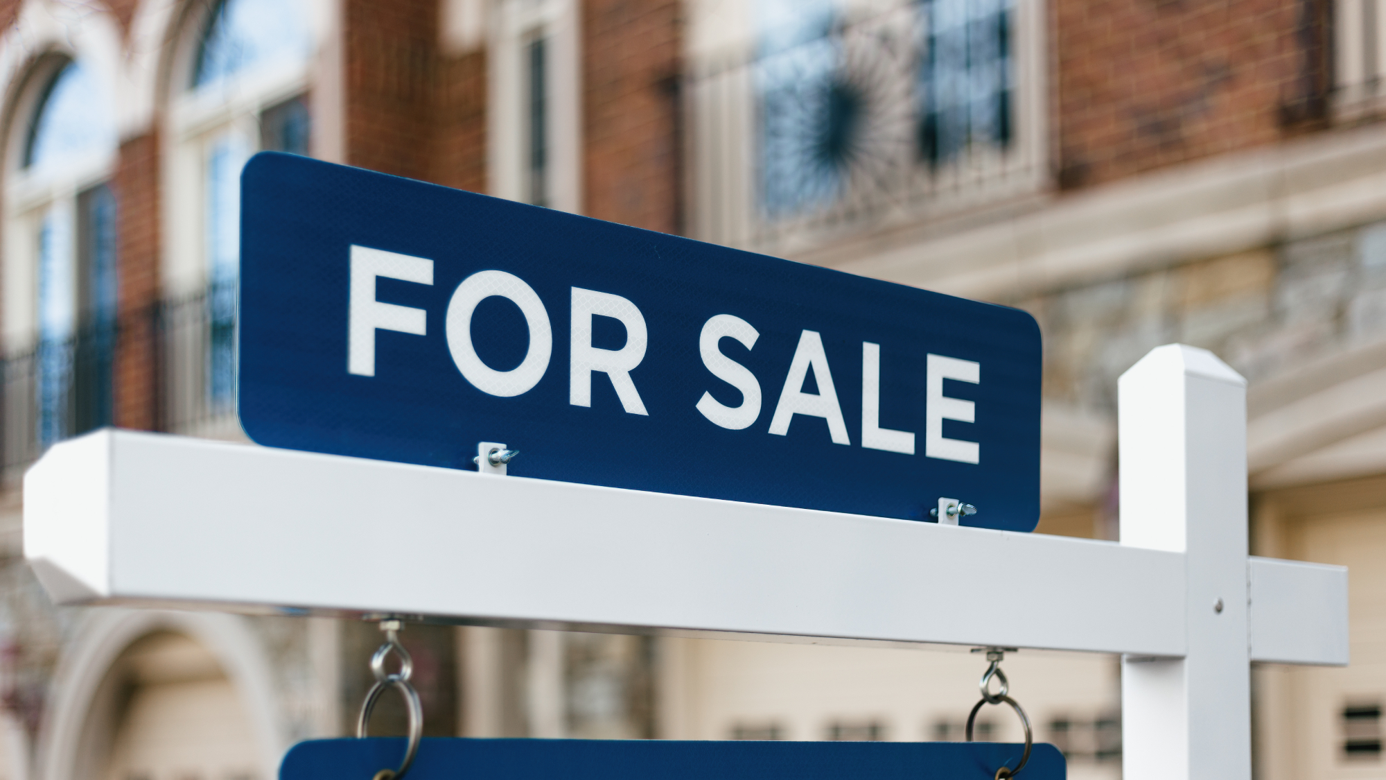 blue and white for sale sign with property in back ground