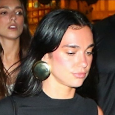 Dua Lipa wearing a black top, zebra bag, dark wash jeans