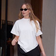 Jennifer Lawrence wearing a white t-shirt and black sunglasses. Her hair is straight and she has on glowy, skin-like makeup. 
