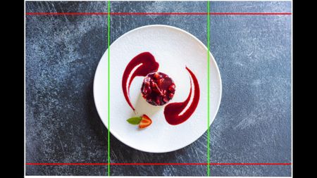A food photo of a strawberry cheesecake on a white plate taken from above and against a dark textured background. There are lines overlaid on top of the image to show the different aspect ratios provided by Open Gate video recording