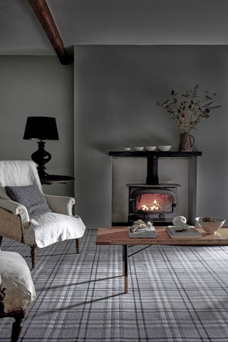 A grey living room with fireplace and grey tartan checked carpet