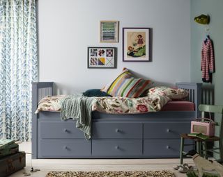 kids' room with gray day bed with storage, green and blue walls, green vintage chair