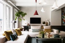 A living room with a brown sofa, a marble coffee table and large tree 