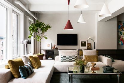 A living room with a brown sofa, a marble coffee table and large tree 