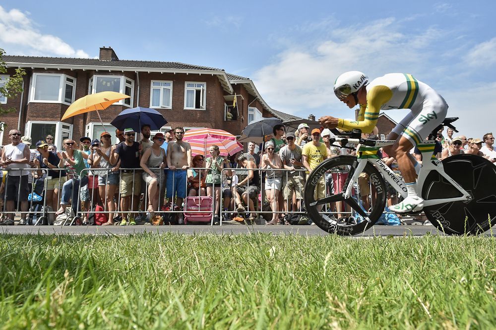 Richie Porte rides past fans who are using umbrellas to shade themselves from the heat.