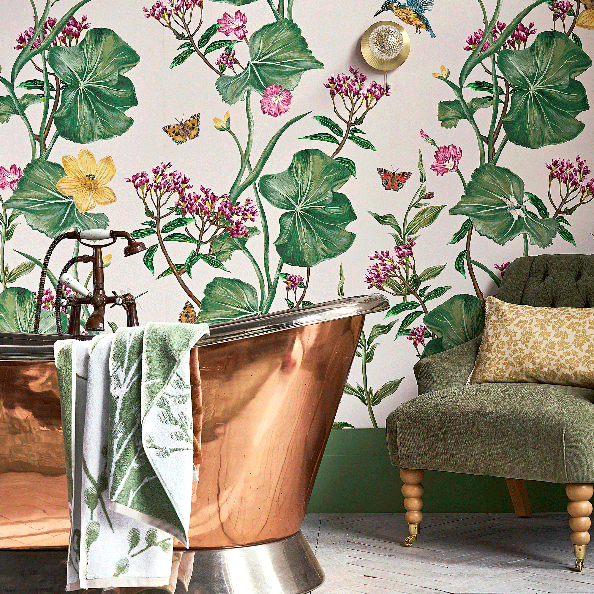 Laura Ashley wall covering featuring flowers and butterflies from The Water&#039;s Edge Collection with a copper bath and green chair