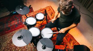 Man with beard playing an Alesis Nitro Pro drum set