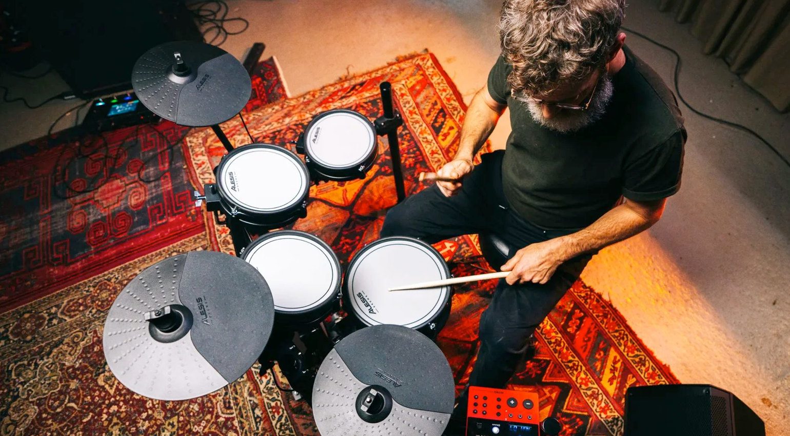 Man with beard playing an Alesis Nitro Pro drum set