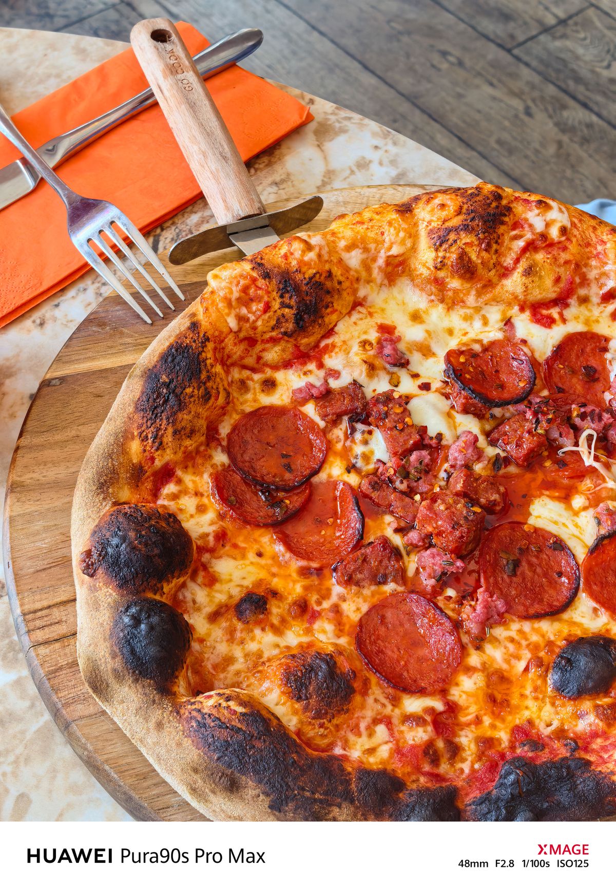 Close-up of a pepperoni and meat pizza with melted cheese and a charred crust on a wooden serving board.