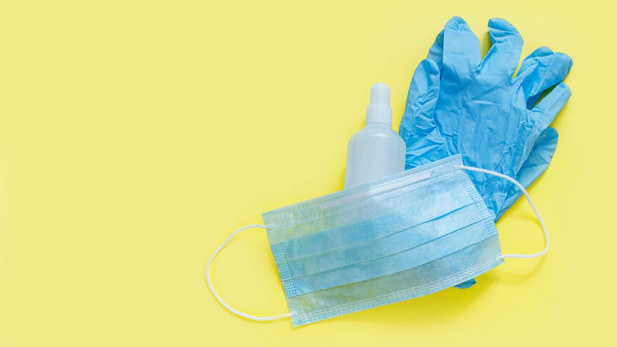 Surgical gloves, mask and hand sanitizer against a yellow background.