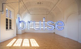 The word "bruise" suspended in a white room with arched ceiling