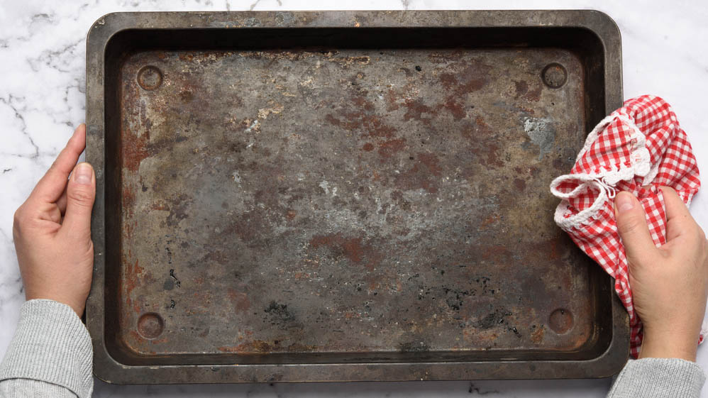 Man holding a dirty baking sheet