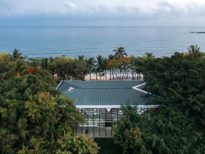 Daytime aerial view showing the Tianya Books by Wutopia Lab in China among trees, sea view and blue cloudy skies