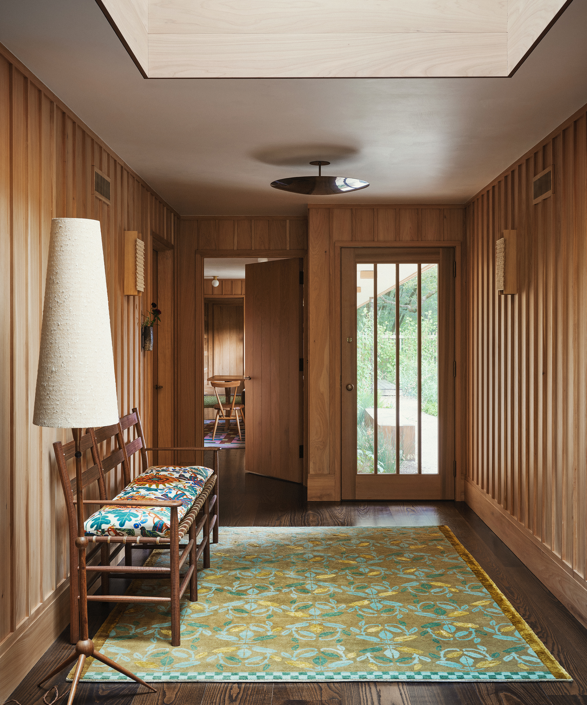 wood entryway with large green rug and wood bench