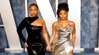 Halle Bailey and Chloe Bailey hold hands on the red carpet.