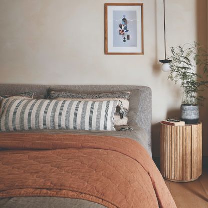 A bedroom with an earthy colour scheme, limewash walls and high-quality bed linen