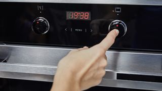 Person changing the time on an oven using a dial. 