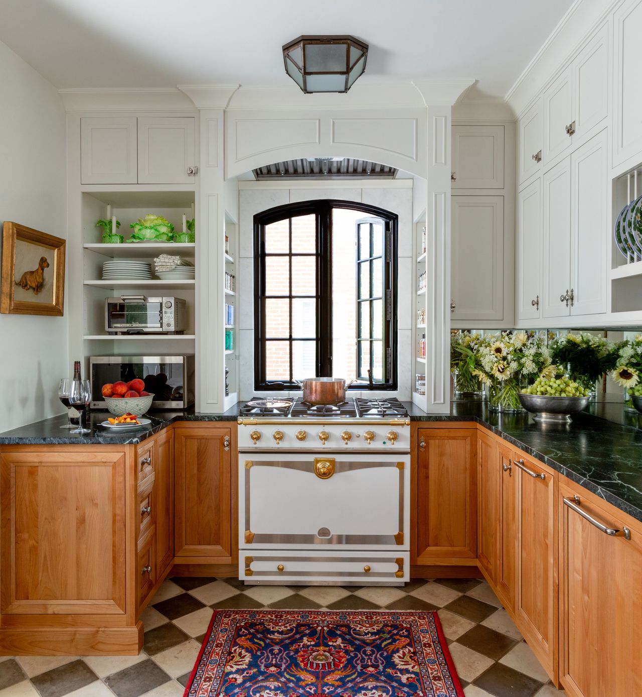 Kitchen with wood cabinets, range, black and white floor tile, rug and white walls